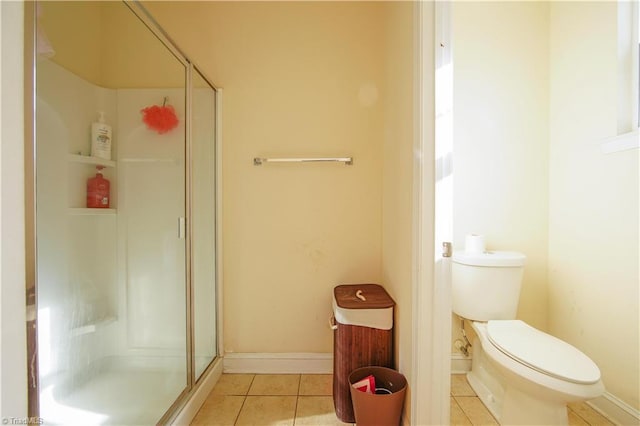 bathroom featuring tile patterned flooring, toilet, and a shower with door