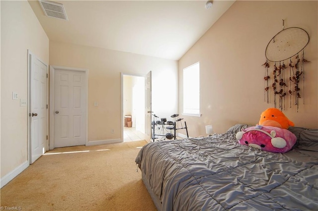 bedroom with light carpet, ensuite bathroom, and vaulted ceiling