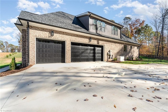 view of home's exterior featuring board and batten siding, driveway, a garage, and fence