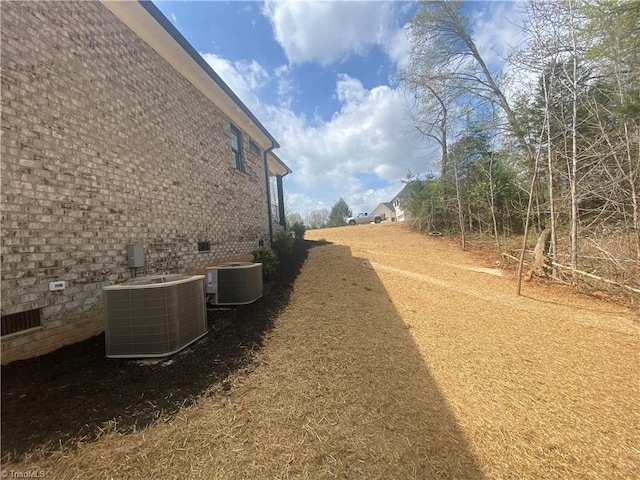 view of side of property with brick siding, crawl space, and central AC unit