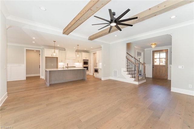 unfurnished living room with sink, crown molding, ceiling fan, beam ceiling, and light hardwood / wood-style floors