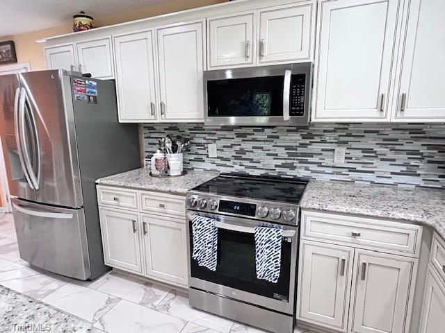 1320 Little Gate Dr, Asheboro, NC 27205 - kitchen with appliances with stainless steel finishes, light marble finish flooring, and white cabinets