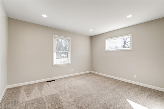 spare room featuring baseboards, carpet flooring, visible vents, and a healthy amount of sunlight