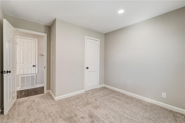 carpeted empty room with baseboards, visible vents, and recessed lighting