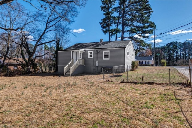 back of property with a chimney, fence, and a yard