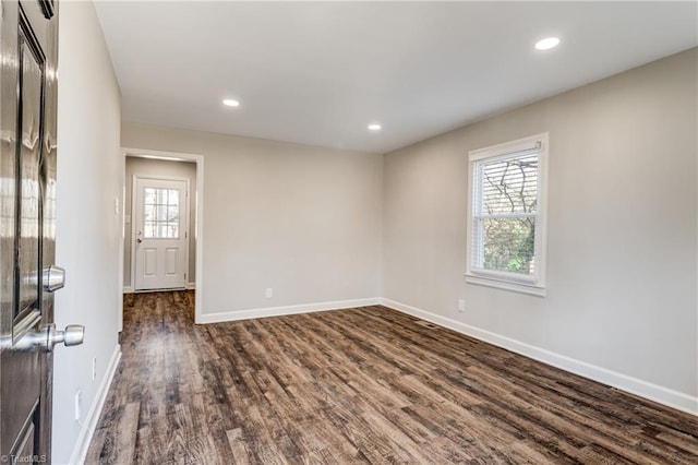 spare room with dark wood-type flooring, a wealth of natural light, and baseboards