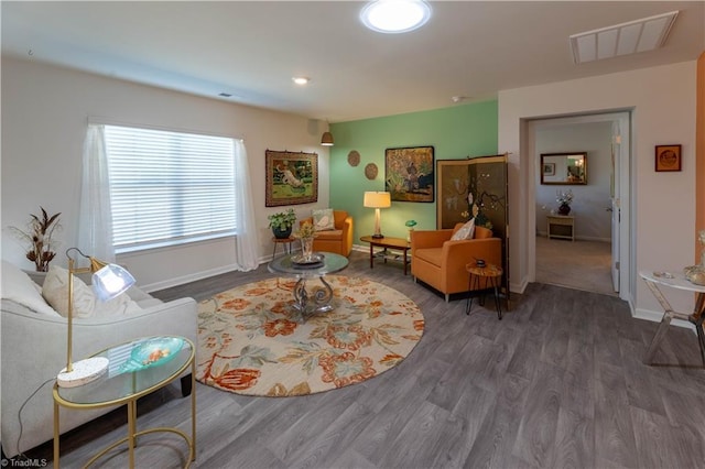 living area with wood finished floors, visible vents, and baseboards