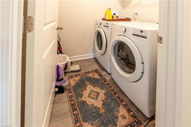 laundry area with laundry area, wood finished floors, washing machine and clothes dryer, and baseboards