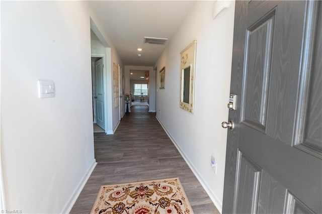 hall featuring baseboards, visible vents, and wood finished floors