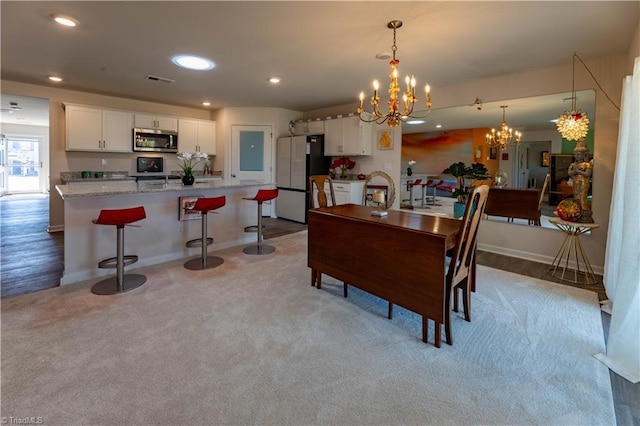 dining space featuring visible vents, baseboards, light colored carpet, an inviting chandelier, and recessed lighting