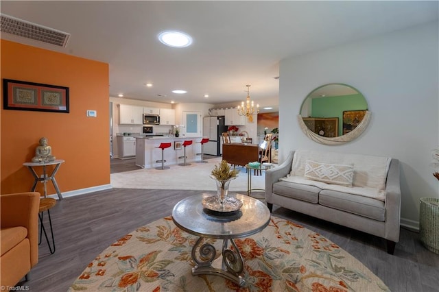 living room with a notable chandelier, recessed lighting, visible vents, wood finished floors, and baseboards