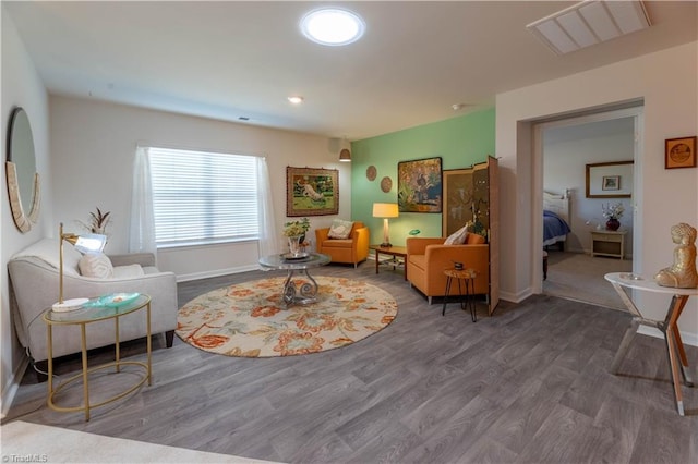 living area with visible vents, baseboards, and wood finished floors