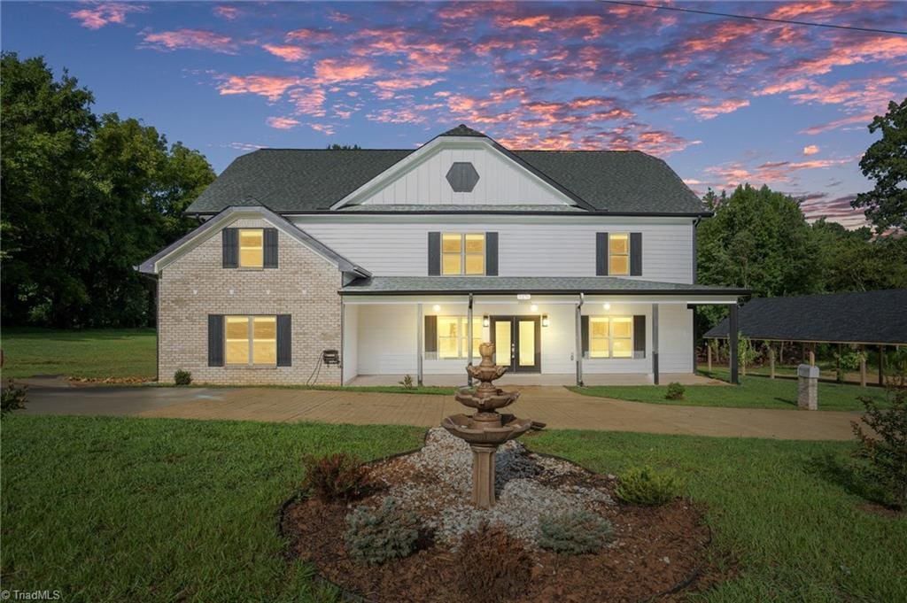 back house at dusk featuring french doors and a lawn