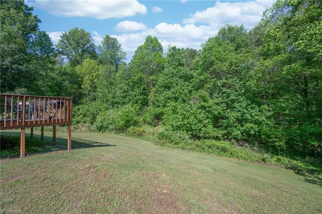 view of yard featuring a wooden deck and a wooded view