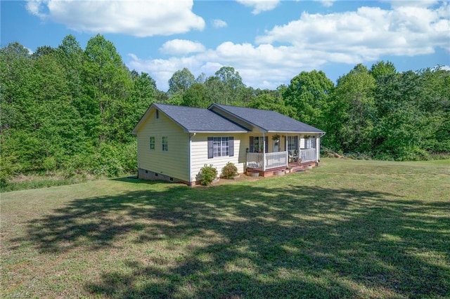 back of property with a lawn, a wooded view, covered porch, and crawl space