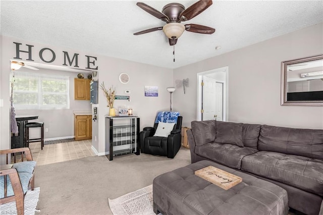 living area featuring a textured ceiling, ceiling fan, and light carpet