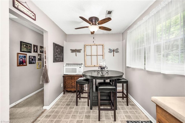 dining area featuring baseboards, a ceiling fan, and visible vents