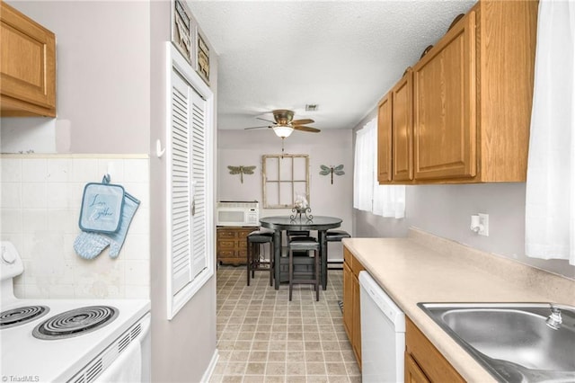 kitchen with a sink, ceiling fan, white appliances, and light countertops