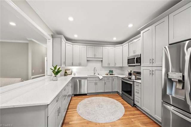 kitchen featuring sink, appliances with stainless steel finishes, ornamental molding, light stone countertops, and kitchen peninsula