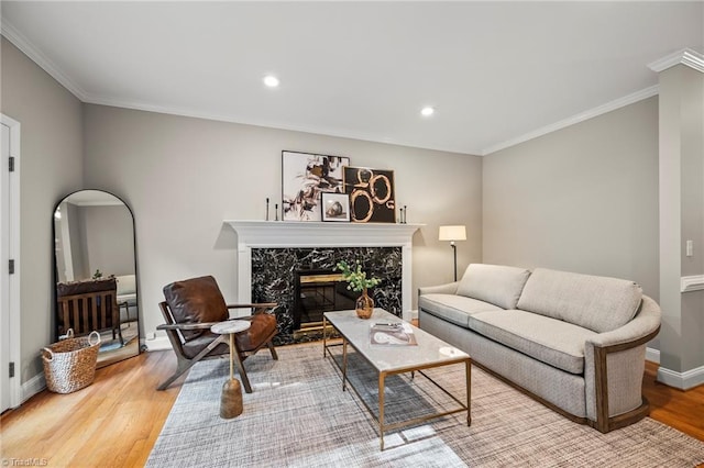 living room with a premium fireplace, crown molding, and light wood-type flooring