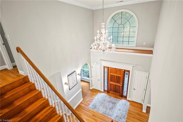 entryway featuring crown molding, plenty of natural light, a chandelier, and light hardwood / wood-style floors