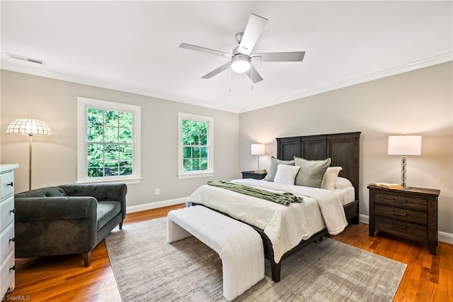 bedroom with crown molding, dark hardwood / wood-style floors, and ceiling fan