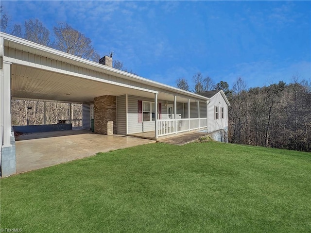 rear view of house with a porch, brick siding, a yard, a carport, and a chimney