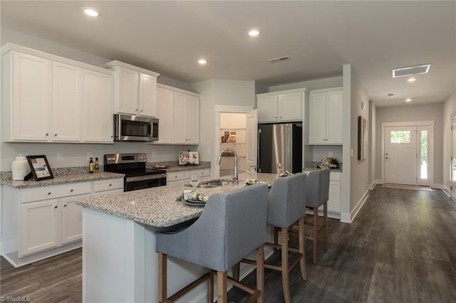 213 Cason Dr, Gibsonville, NC 27249 - kitchen featuring stainless steel appliances, a sink, a kitchen bar, white cabinets, and recessed lighting