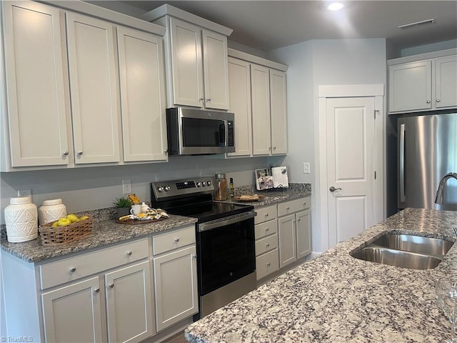 213 Cason Dr, Gibsonville, NC 27249 - kitchen with appliances with stainless steel finishes, a sink, and light stone countertops