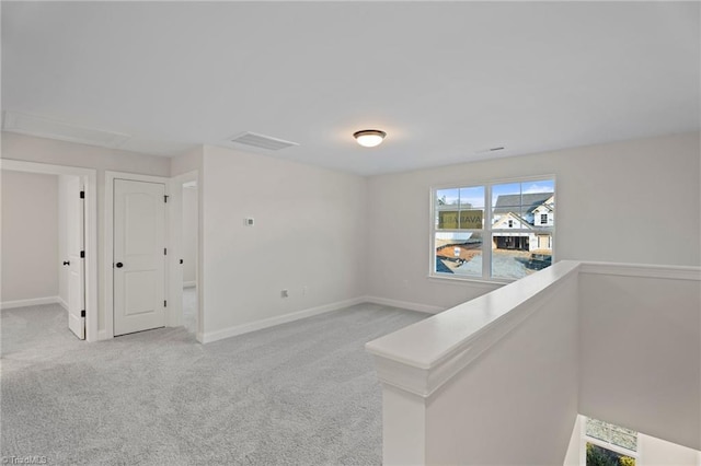 spare room with light colored carpet, visible vents, and baseboards