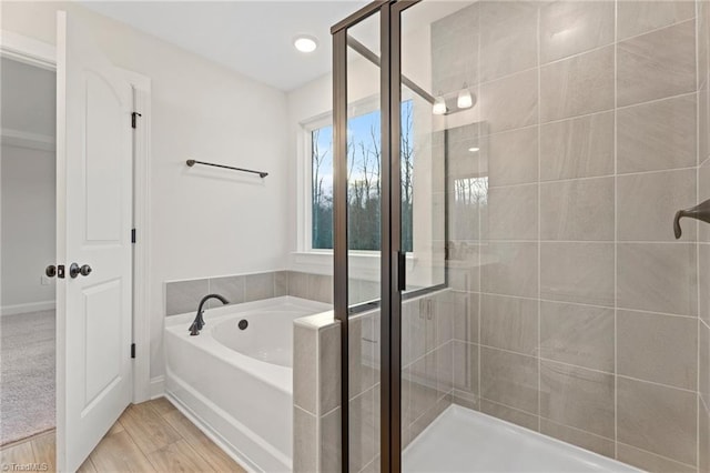 full bath with wood finished floors, a stall shower, and a garden tub