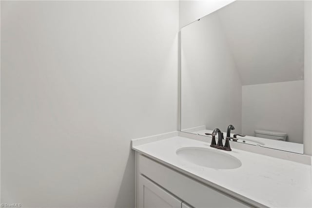 bathroom featuring vaulted ceiling, toilet, and vanity