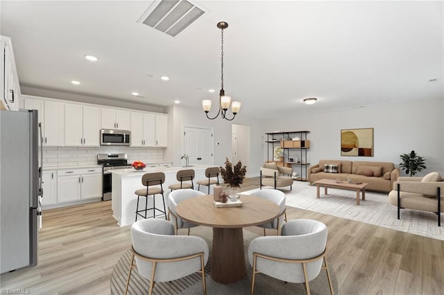 dining space featuring light wood-style floors, visible vents, a chandelier, and recessed lighting