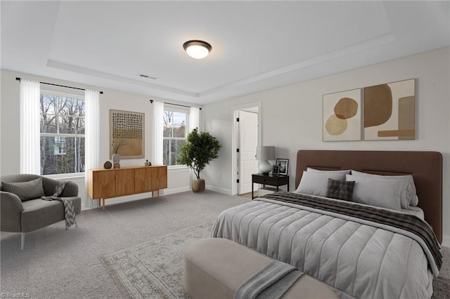 bedroom with light carpet, visible vents, a tray ceiling, and baseboards