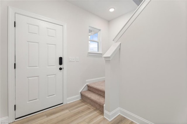 foyer entrance with stairway, light wood-style flooring, and baseboards