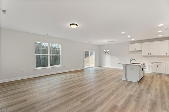 kitchen with light wood-style flooring, a sink, open floor plan, light countertops, and backsplash