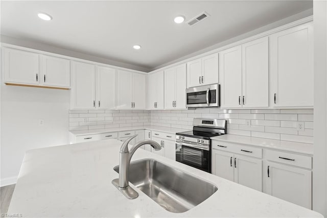 kitchen featuring stainless steel appliances, tasteful backsplash, a sink, and white cabinets