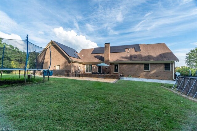 4905 Deer Pointe Ct, Greensboro, NC 27406 - back of house with fence, a patio, a trampoline, solar panels, and a lawn