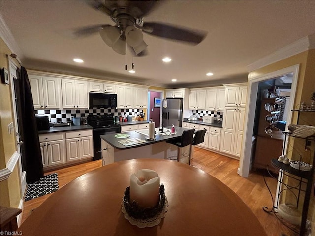 kitchen with a center island, white cabinets, appliances with stainless steel finishes, tasteful backsplash, and light hardwood / wood-style floors