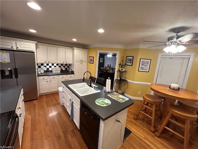 kitchen with black appliances, sink, ceiling fan, an island with sink, and tasteful backsplash