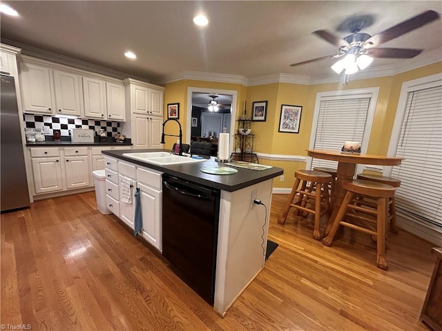 kitchen featuring decorative backsplash, sink, a center island with sink, black dishwasher, and white cabinetry