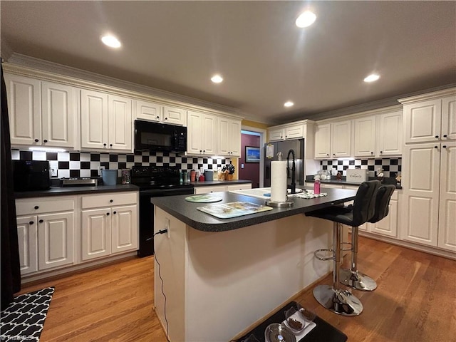 kitchen with a kitchen breakfast bar, light hardwood / wood-style floors, a kitchen island, and stainless steel electric range