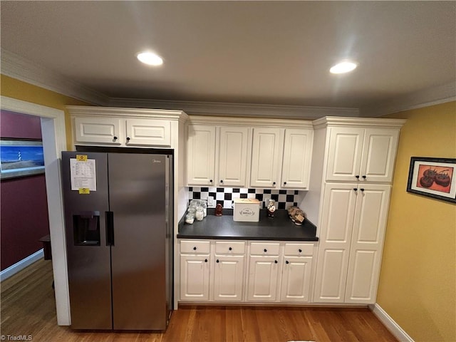 kitchen featuring white cabinetry, stainless steel fridge with ice dispenser, crown molding, decorative backsplash, and hardwood / wood-style flooring