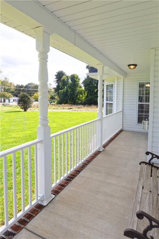 wooden deck with a lawn and covered porch