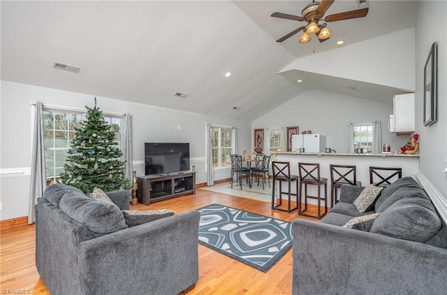 living room with ceiling fan, vaulted ceiling, and light wood-type flooring