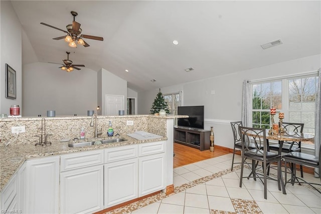 kitchen with ceiling fan, white cabinetry, sink, and vaulted ceiling