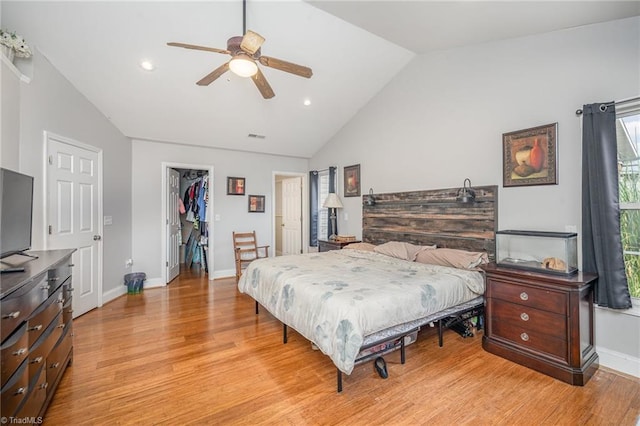 bedroom with ceiling fan, high vaulted ceiling, light hardwood / wood-style floors, a walk in closet, and a closet