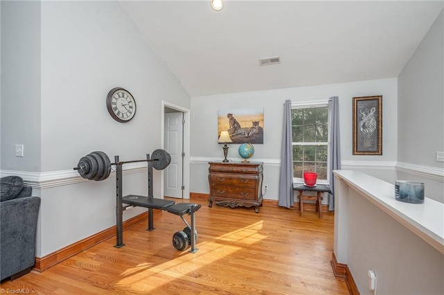 workout room featuring vaulted ceiling and light hardwood / wood-style flooring