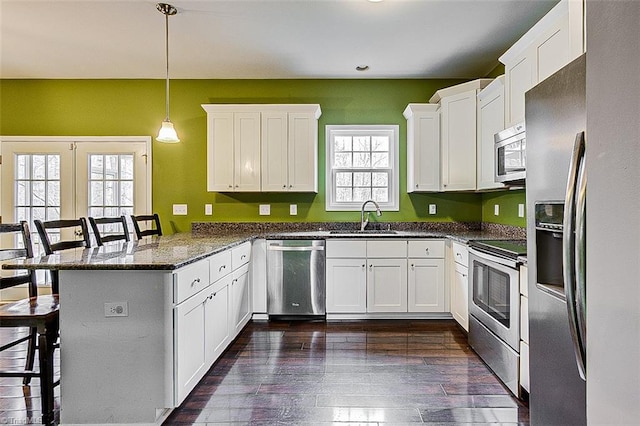 kitchen with a sink, a kitchen breakfast bar, white cabinetry, stainless steel appliances, and a peninsula