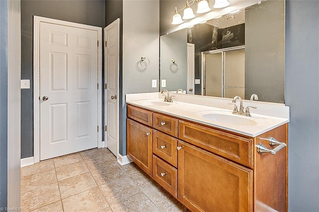 bathroom featuring a shower stall, double vanity, baseboards, and a sink